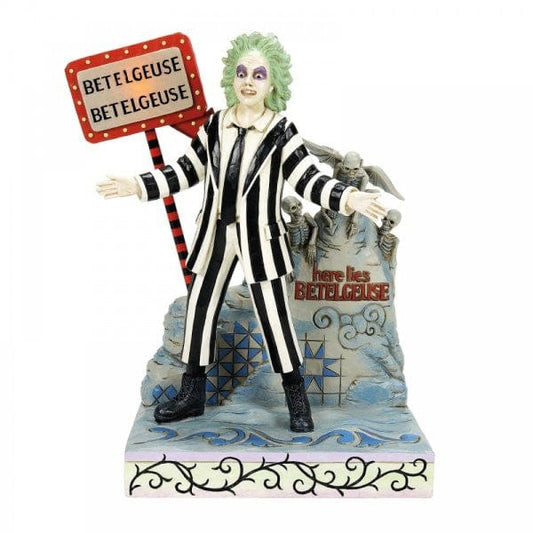 A figure of Beetlejuice in a black-and-white striped suit stands in front of a tombstone with here lies Beetlejuice and a sign reading BETELGEUSE three times. Skeletons and dark patterns decorate the base. A figure of Beetlejuice in a black-and-white striped suit stands in front of a tombstone with here lies Beetlejuice and a sign reading BETELGEUSE three times. Skeletons and dark patterns decorate the base.