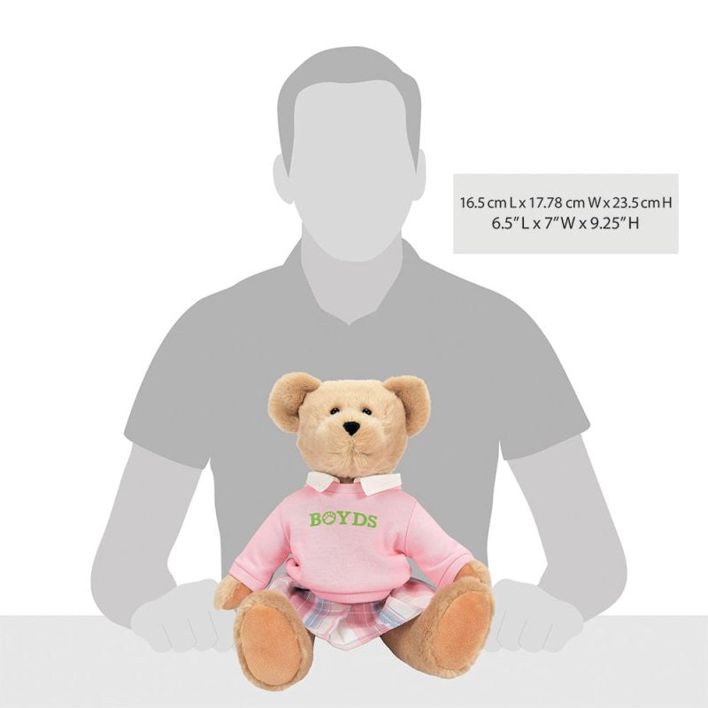 The Emma Boydsley Bear 14 Inch Plush Soft Toy by Boyds Bears wears a pink BOYDS sweater and plaid skirt. Dimensions: 6.5L x 7W x 9.25H. Shown before a grayscale silhouette of a seated person. Brand: Boyds Bears.