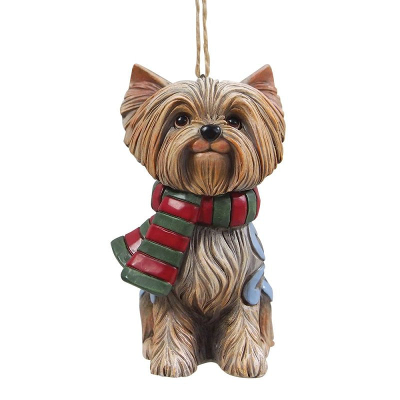 The Heartwood Creek By Jim Shore Christmas Yorkie Hanging Ornament 6017528 features a festive Yorkshire Terrier in a scarf and blue vest, sitting upright with a hanging string—ideal for holiday decoration.