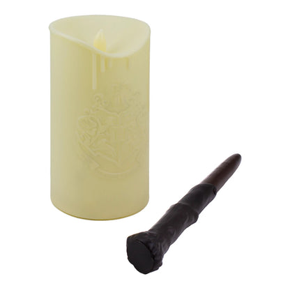 The Harry Potter Candle With Wand Remote Control Light by Paladone, in cream with an embossed Hogwarts crest, stands upright beside a black wand-shaped remote.