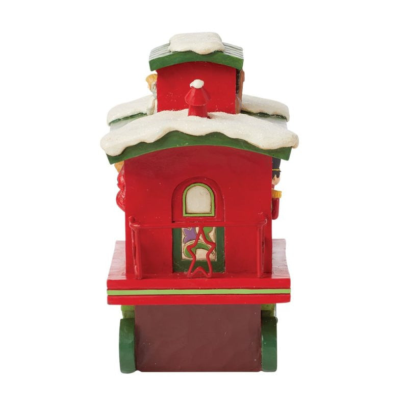 The Heartwood Creek By Jim Shore North Pole Delivery Train Car Caboose Figurine (6015481) is a festive red caboose with snow on the roof, green trim, wheels, North Pole Delivery details, and a gingerbread person in the window.
