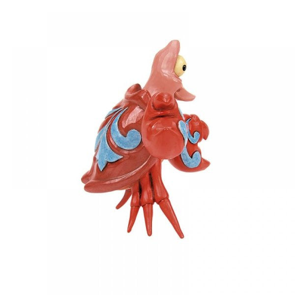The Disney Traditions Sebastian Mini Figurine by Jim Shore 6015021 features a red ceramic crab with exaggerated features, blue shell accents, and a large yellow eye. It stands on pointed legs against a white background.