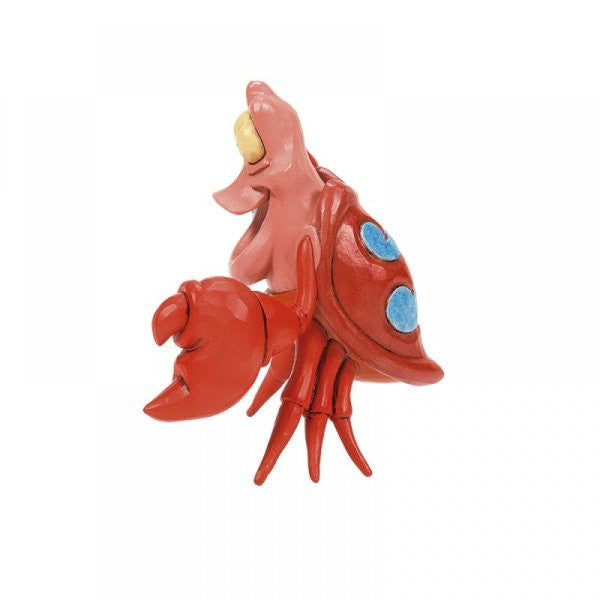 The Disney Traditions Sebastian Mini Figurine by Jim Shore (6015021) features a red cartoon crab with a pink face, open mouth, large claw, blue shell spots, and multiple red legs—standing upright against a white background.