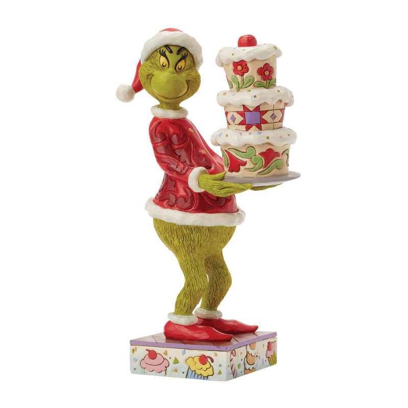 The Grinch with A Grinchy Cake Figurine By Jim Shore 6017069 features The Grinch in a Santa suit, smiling mischievously while holding a festive cake—an ideal holiday decor piece from The Grinch By Jim Shore collection.