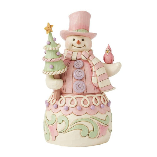 The Heartwood Creek by Jim Shore Pastel Winter Wonders (Pastel Candy Snowman) Figurine 6017019 features a pastel snowman in a pink hat and scarf, holding a decorated tree with a pink bird and ornate base patterns.