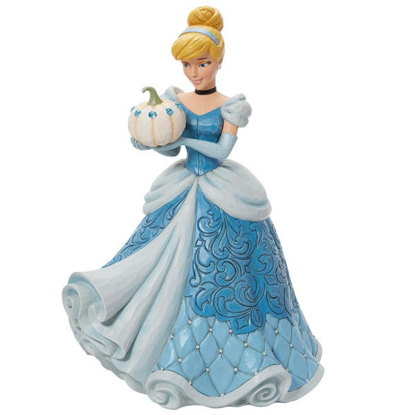 The Enesco Disney Traditions The Iconic Pumpkin Cinderella Deluxe Figurine by Jim Shore (6013078) features Cinderella in a blue ball gown, white gloves, and headband, holding a gem-studded pumpkin with her blonde hair in an elegant bun.