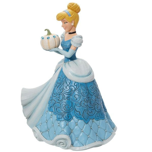 The Enesco Disney Traditions The Iconic Pumpkin Cinderella Deluxe Figurine by Jim Shore (6013078) features Cinderella in a blue gown with detailed patterns, holding a white pumpkin with blue accents and styled in her classic updo.