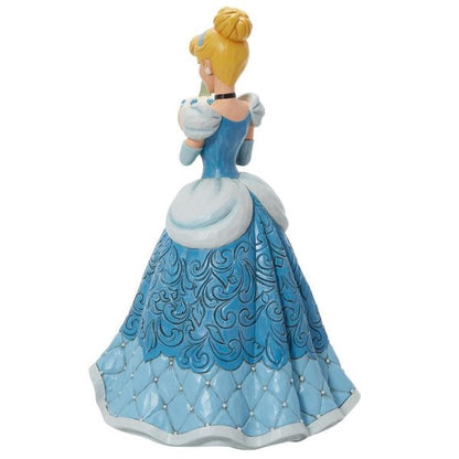 The Enesco Disney Traditions The Iconic Pumpkin Cinderella Deluxe Figurine by Jim Shore (6013078) shows Cinderella facing away in a blue gown with white accents, detailed skirt patterns, and her blonde hair in a bun with a blue headband.