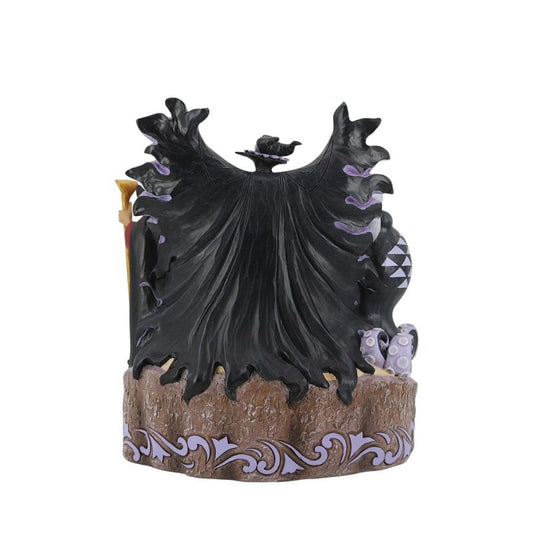 The Enesco Disney Traditions Villains Carved by Heart By Jim Shore 6010880 figurine features a villain with a flowing black cape, viewed from the back, on an ornate brown and purple base with detailed patterns.