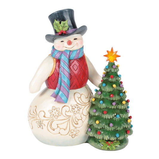 The Heartwood Creek By Jim Shore All Is Merry & Bright (Snowman with Vintage LED Tree) Figurine 6017016 features a festive snowman in a top hat and scarf beside a vintage LED tree with a yellow star, perfect for your holiday décor.