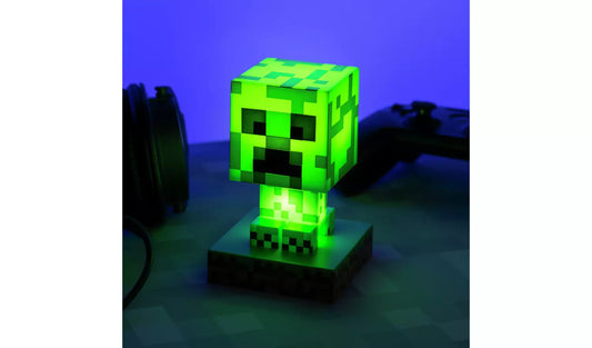 The Minecraft Creeper Icon Light by Paladone glows green atop a square base, brightening your desk. Accompanied by a gaming controller and headphones, it’s the perfect addition for any video game fan.