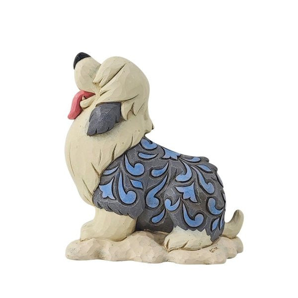 The Disney Traditions Max Mini Figurine 6014334 features a dog sitting with head tilted up, tongue out, and intricate blue-gray patterns on cream fur—perfect for collectors of Disney Traditions or The Little Mermaid.