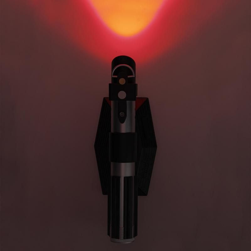 The Star Wars Lightsaber Uplighter by Paladone features a sleek black and silver cylindrical design inspired by Darth Vader’s lightsaber, emitting an orange-red glow upwards. This is an officially licensed Star Wars product from Paladone.