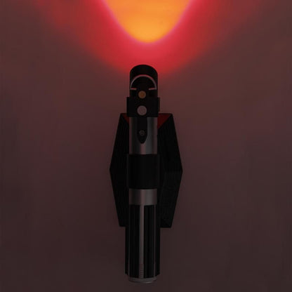 The Star Wars Lightsaber Uplighter by Paladone features a sleek black and silver cylindrical design inspired by Darth Vader’s lightsaber, emitting an orange-red glow upwards. This is an officially licensed Star Wars product from Paladone.