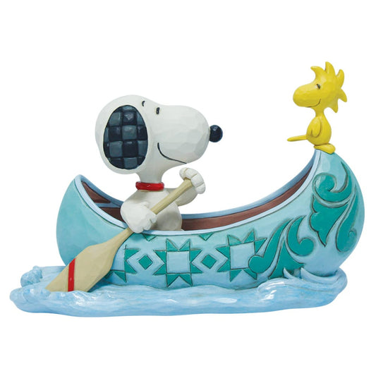 The Snoopy & Woodstock Canoe Figurine by Peanuts By Jim Shore features Snoopy paddling a patterned blue canoe with Woodstock up front, floating on stylized blue water.