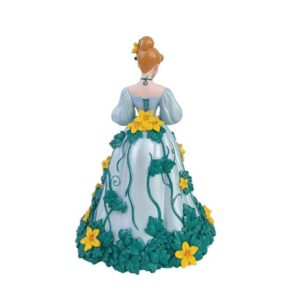 The Enesco Disney Showcase Cinderella Botanical Figurine 6015332 features Cinderella in a light blue dress with green vines and yellow flowers, viewed from behind, her brown hair in a bun topped with a yellow flower.