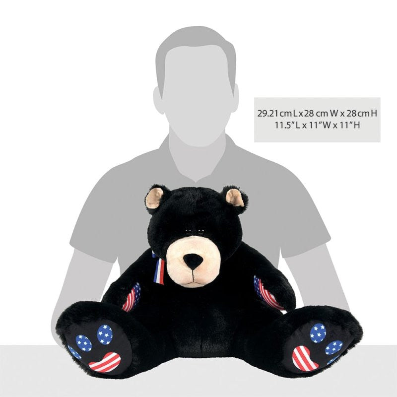 A 16-inch black Bubba Bearsevelt Bear plush by Boyds Bears, model 6017140, featuring American flag patches on its paws and arms, sits before a grayscale silhouette. Dimensions: 29.21 x 28 x 28 cm (11.5 x 11 x 11 in).