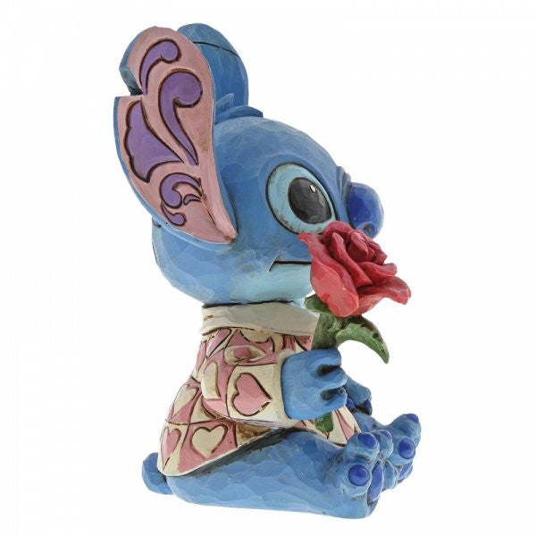 Disney Traditions Stitch the adorable alien from Lilo & Stitch wears a heart-patterned shirt as he offers a single red rose figurine