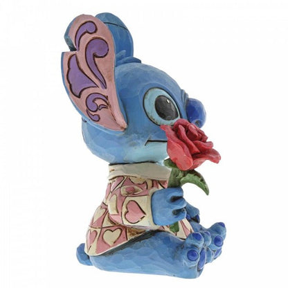 Disney Traditions Stitch the adorable alien from Lilo & Stitch wears a heart-patterned shirt as he offers a single red rose figurine