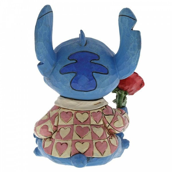 Disney Traditions Stitch the adorable alien from Lilo & Stitch wears a heart-patterned shirt as he offers a single red rose figurine