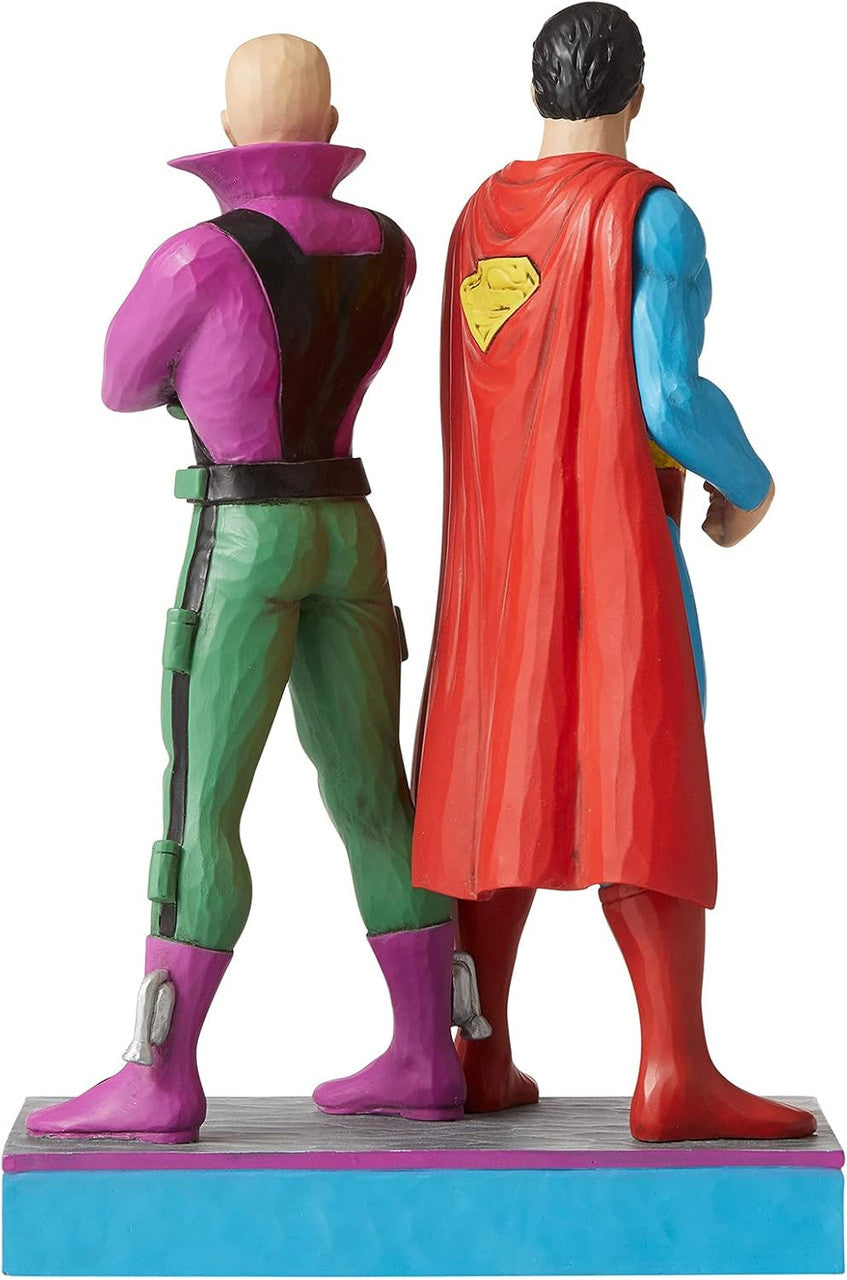 The DC Superman and Lex Luthor Figurine By Jim Shore features two painted figures standing side by side: Superman in his iconic suit and red cape, and Lex Luthor in a purple and green outfit. From DC Comics By Jim Shore.