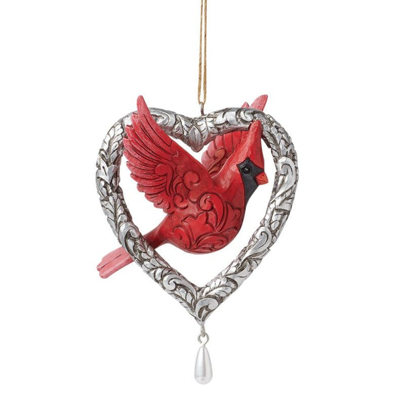The Heartwood Creek By Jim Shore Forever In My Heart (Caring Cardinal) Hanging Ornament features a detailed red cardinal inside a silver heart-shaped frame with intricate designs and a dangling white teardrop bead.
