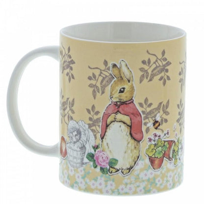 The Beatrix Potter Flopsy Bunny Mug features a rabbit in a red cape with flowers, a basket, and potted plants on a light yellow floral-patterned background—a charming tribute to the beloved classic.