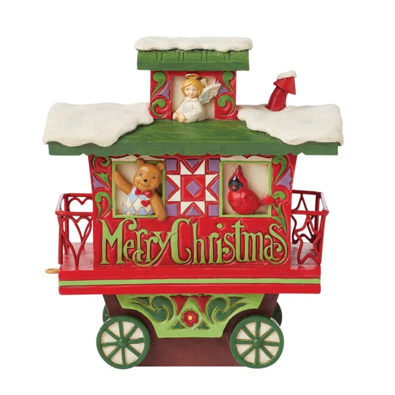 The Heartwood Creek By Jim Shore North Pole Delivery Train Car Caboose Figurine 6015481 features a festive, snow-covered caboose with a Merry Christmas sign, teddy bear, red cardinal, and angel in classic red, green, and gold Jim Shore style.
