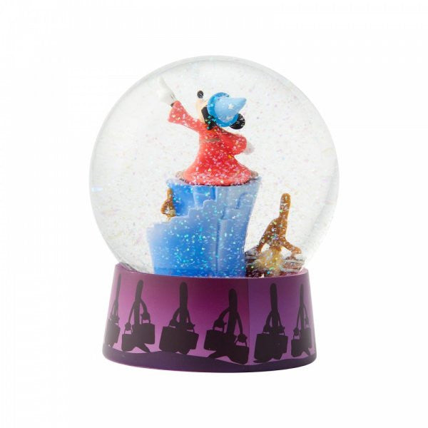 The Enesco Disney Showcase Sorcerer Mickey Fantasia Waterball 6004109 features Sorcerer Mickey in a red robe and blue hat standing on an icy base with glitter inside, and a purple base decorated with black handbag and people silhouettes.