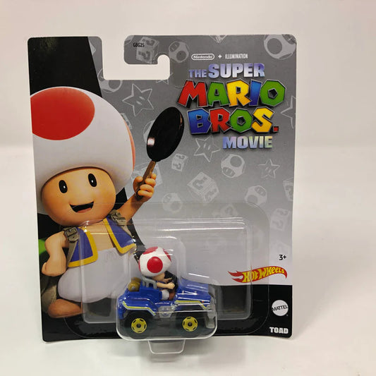 The Hot Wheels Mario Kart Toad Super Mario Bros. Movie die-cast car features Toad driving a blue vehicle, with packaging showing Toad holding a frying pan. Both the Hot Wheels and Mario logos are clearly displayed on the package.