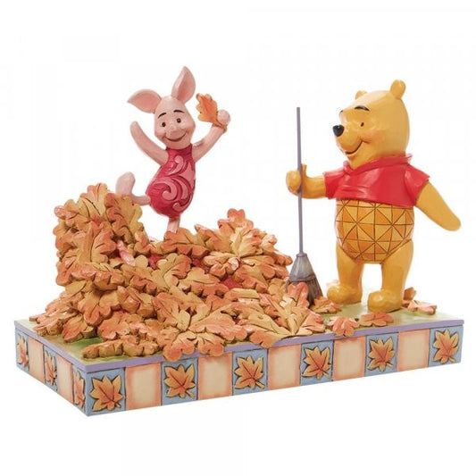 Disney Traditions Winnie the Pooh rakes a yard-full of leaves into a giant pile while Piglet prepares to leap into it figurine