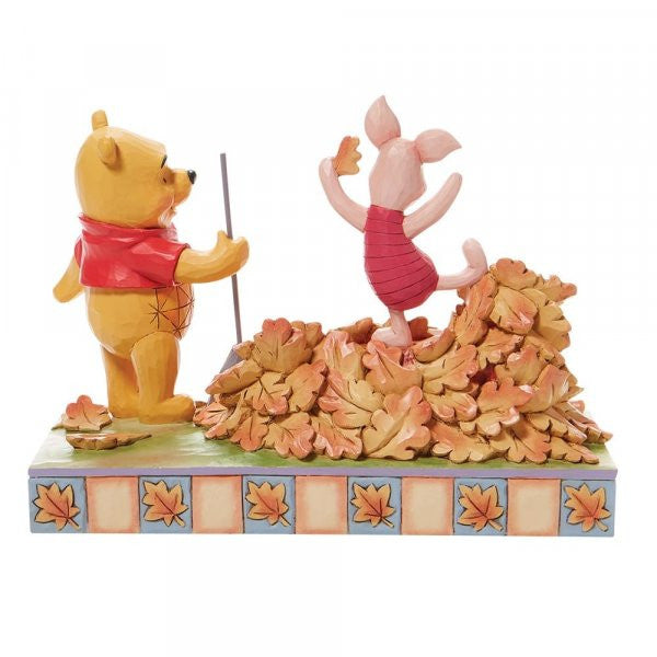 Disney Traditions Winnie the Pooh rakes a yard-full of leaves into a giant pile while Piglet prepares to leap into it figurine