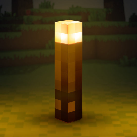 The Minecraft Torch Light By Paladone stands upright on a blocky green surface with a glowing background; this fun, table-mountable lamp by Paladone is perfect for fans of the iconic game.