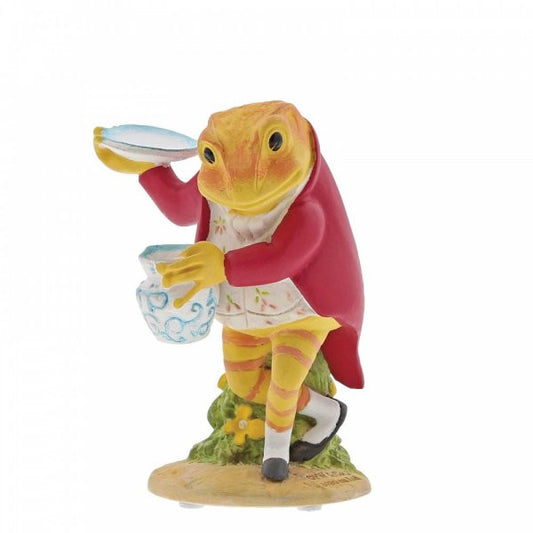 The Beatrix Potter Mr. Jeremy Fisher in the Larder Figurine is a ceramic toad in a red coat and vest, holding a blue and white dish and jug on grassy ground with a yellow flower—a charming collectible for fans.
