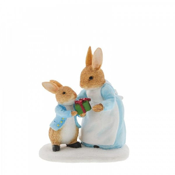 The Beatrix Potter Mrs. Rabbit Passing Peter Rabbit a Present Figurine features two rabbits in blue jackets, with the little one giving a red gift on a white base—a heartwarming holiday keepsake.