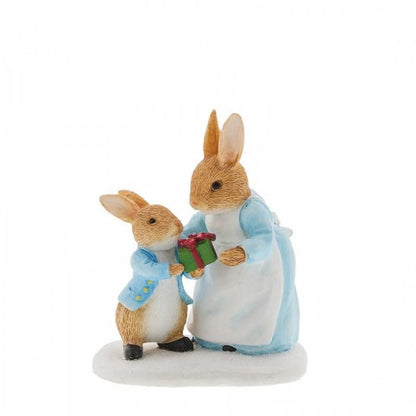 The Beatrix Potter Mrs. Rabbit Passing Peter Rabbit a Present Figurine features two rabbits in blue jackets, with the little one giving a red gift on a white base—a heartwarming holiday keepsake.