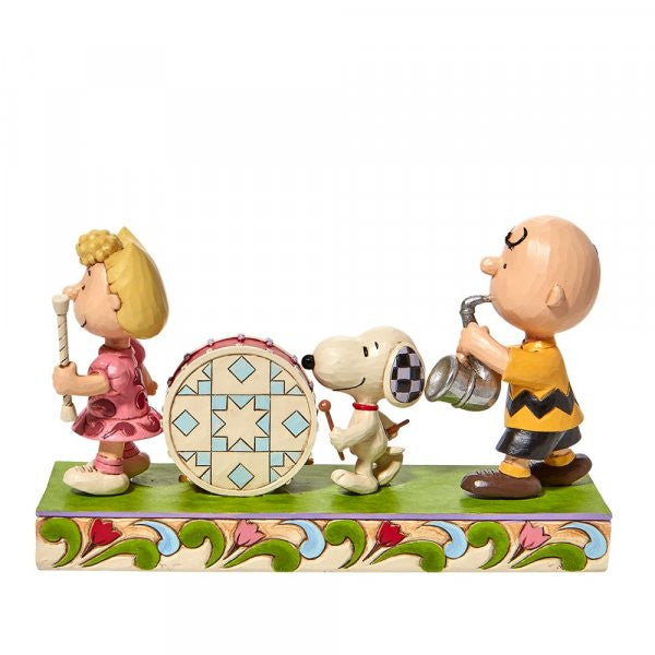 The Peanuts Parade Figurine by Jim Shore features Sally with a flute, Snoopy on drums, and Charlie Brown playing saxophone, all atop a vibrant base with signature Jim Shore patterns. Brand: Peanuts By Jim Shore.