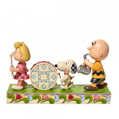 The Peanuts Parade Figurine by Jim Shore features Sally with a flute, Snoopy on drums, and Charlie Brown playing saxophone, all atop a vibrant base with signature Jim Shore patterns. Brand: Peanuts By Jim Shore.