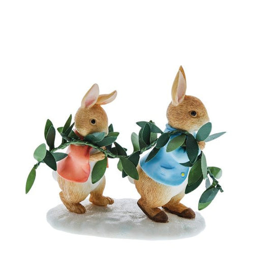 The Beatrix Potter Peter Rabbit & Flopsy Figurine features two rabbits in blue and red jackets holding leafy branches, standing on a white winter-themed base.