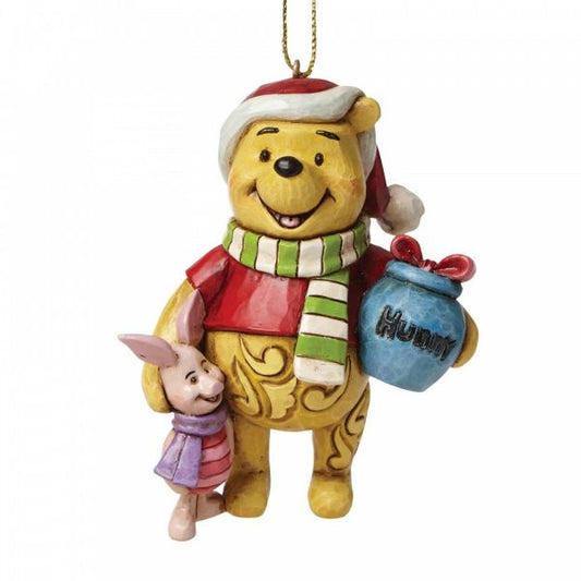 The Disney Traditions Winnie the Pooh and Piglet Hanging Ornament (A27551) features Pooh in a Santa hat with a blue Hunny pot beside Piglet, adding festive cheer to any Christmas tree.
