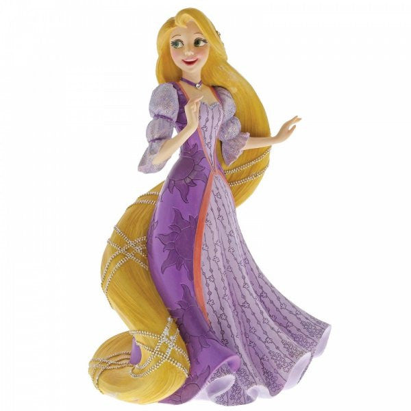 The Disney Showcase Rapunzel Figurine 6001661 features Rapunzel from Tangled, with long braided blonde hair adorned with flowers, wearing a purple dress with puffed sleeves and floral details, standing and smiling.