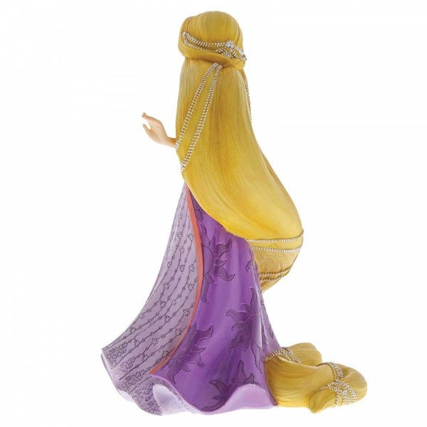 The Disney Showcase Rapunzel Figurine 6001661 features Rapunzel in a purple gown with long, pearl-adorned blonde hair trailing to the floor, crafted from cast stone and inspired by Disney’s Tangled.