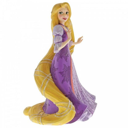 The Disney Showcase Rapunzel Figurine 6001661 features Rapunzel from Tangled with long blond braided hair and a purple dress with floral designs, crafted from high-quality cast stone.