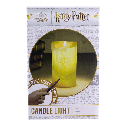 The Paladone Harry Potter Candle With Wand Remote Control Light comes in packaging with a golden Hogwarts crest and text highlighting the magic wand remote. A newspaper-style background adds an extra magical touch.