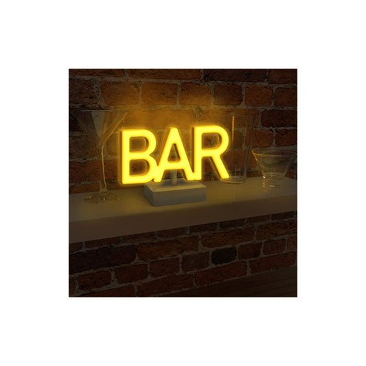The Bar LED Neon Light by Paladone glows yellow as it sits freestanding on a shelf beside martini glasses—an eye-catching decor piece from Paladone, perfect for any home bar.