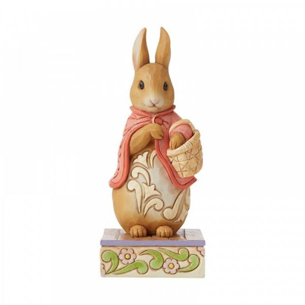 The Good Little Bunny Flopsy Bunny Figurine by Jim Shore from Beatrix Potter features a brown rabbit in a red cape with a basket, standing on a floral base—perfect for Peter Rabbit collectors.