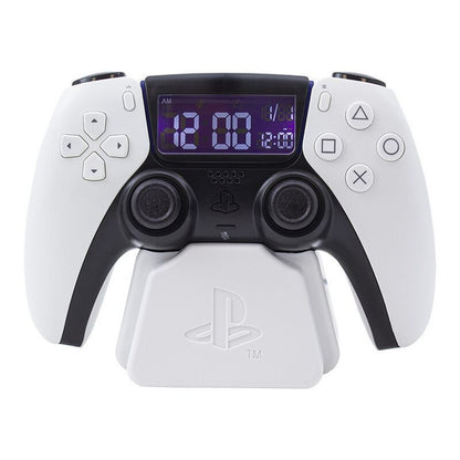 The Playstation 5 Controller Alarm Clock by Paladone features a white PS5 DualSense controller design with a digital clock display showing white numbers on a blue background, resembling an alarm clock. Brand: Paladone.