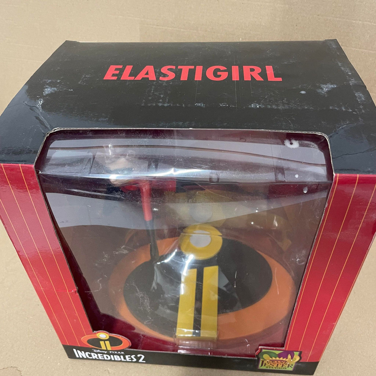 A DAMAGED BOX Grand Jester Studios Disney Mrs Incredible Vinyl Figurine, displayed in black and red packaging with a clear window and ELASTIGIRL in bold at the top.