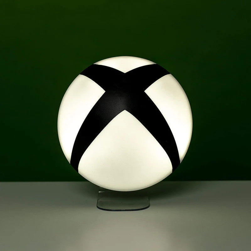 The Xbox Logo Light by Paladone features a round, white design with a bold black X, displayed on a clear stand against a dark green background—a stylish decor piece for gamers and Xbox fans.