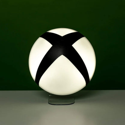 The Xbox Logo Light by Paladone features a round, white design with a bold black X, displayed on a clear stand against a dark green background—a stylish decor piece for gamers and Xbox fans.